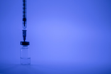 Vaccine vial, syringe with flu shot needle, vaccination medical concept, subcutaneous injection on blue background. Copy space. Test immunization and vaccination laboratory. Healthcare and medicine