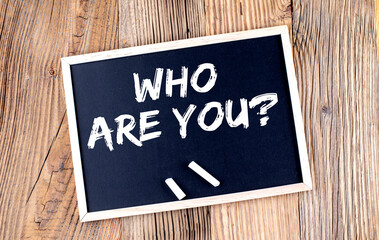 WHO ARE YOU text on a chalkboard on the wooden background