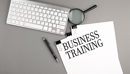 BUSINESS TRAINING text on paper with keyboard on grey background