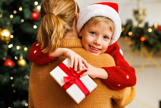 Cheerful child congratulating  mother at Christmas