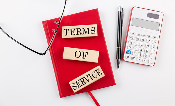 TERMS OF SERVICE text on wooden block on red notebook