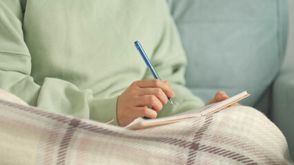 author scribbles notes in a notebook. young woman with pencil writing to diary at cozy home note. Scandinavian style, hygge concept. break from burnout and digital overload