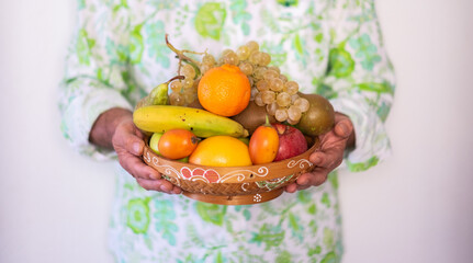 Mature man carries a basket full of fresh fruit. Healthy eating and wellness concept.