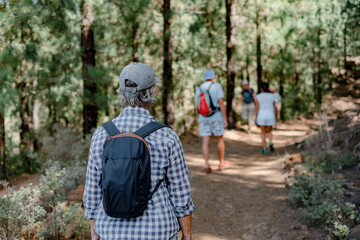 Back view of a group of older caucasian people walking the trail on a mountain hike enjoying free...