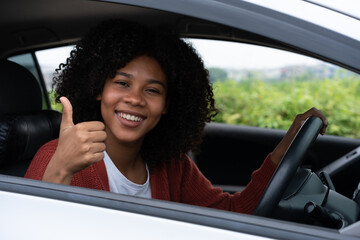 Young woman half asian half African shows thumb up inside of new modern car. Young woman excitement...