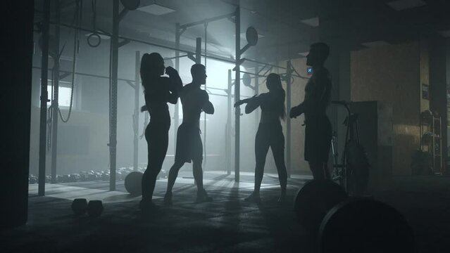 group of sporty person training in gym, two brawny men and two attractive women are warming muscles