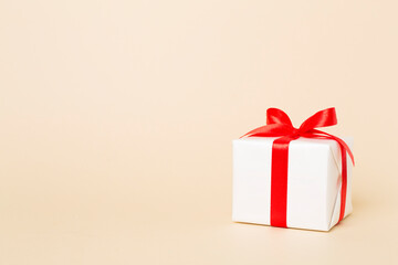 Obraz premium Gift box with red ribbon bow on color background