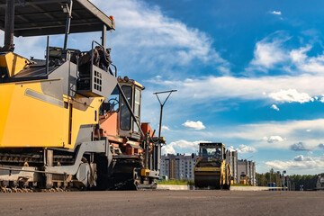 Asphalt laying equipment. Work on the device of a new road surface in a modern city. Powerful construction equipment for landscaping.