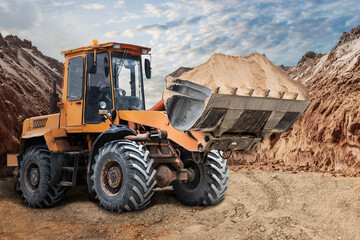 Bulldozer or loader moving sand on a construction site in a pit. An earthmoving machine is leveling the site. Heavy construction equipment for earthworks. Territory improvement.