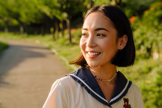 Young smiling asian woman walking in park