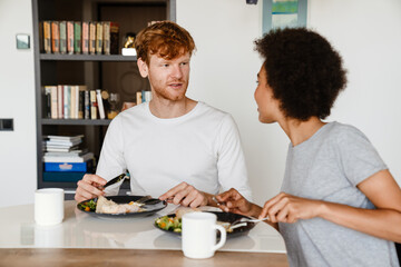 Young beautiful interracial couple looking at each other during breakfast