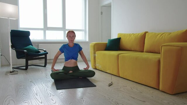 Adult woman doing yoga in the living room with smoldering incense on the floor