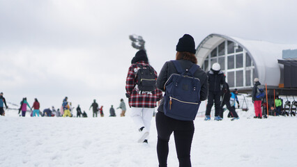 Holiday lifestyle, young female tourist in winter coat wearing knitted hat and backpack walking in the snow. One of the skiing destinations