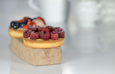 Two mixed berries curd tarts on white table