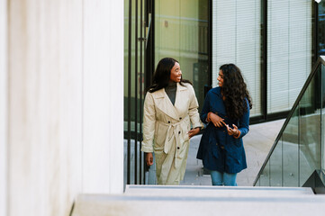 Two young multinational women walking through the city street