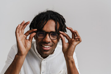 Joyful man adjusting glasses and looking at camera isolated over white background