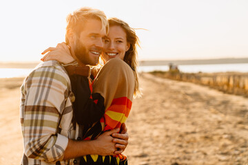 Happy young white couple hugging and walking by seashore