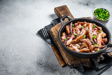 Fried spicy pork pig ears served in a frying pan. white background. Top view. Copy space