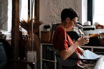 European woman drinking coffee and working with tablet computer