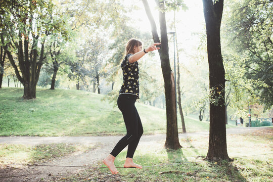 Athletic sportive fit woman practicing slacklining outdoors in park