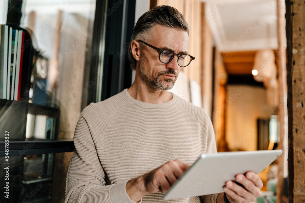 Wall mural white middle-aged man using tablet computer while working in office