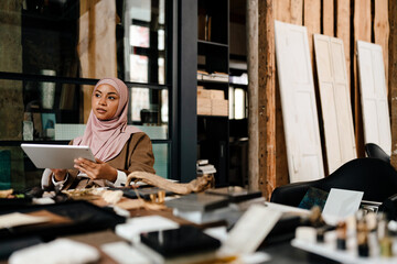 Arabian woman designer working on tablet at workshop