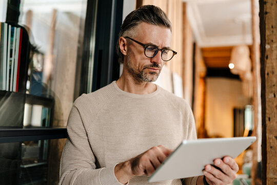 White middle-aged man using tablet computer while working in office