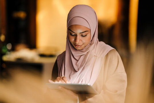 Arabian woman working on tablet while standing indoors