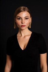 Young beautiful woman looking at camera while standing isolated over black background