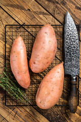 Raw sweet potatoes on kitchen table, fresh batata. Wooden background. Top view