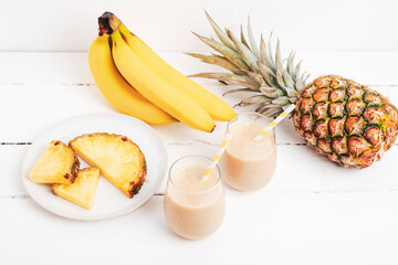 Banana and pineapple smoothie on white wooden table with ingredients. Detox diet concept, summer...