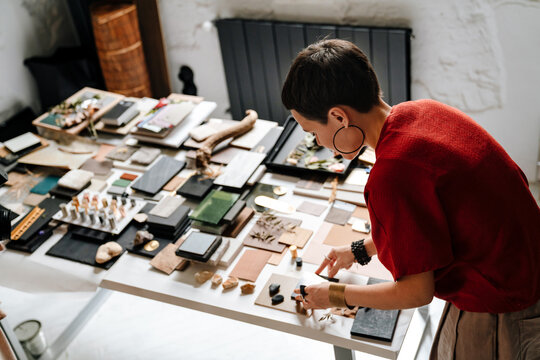 White female interior designer working at her workshop standing with back to camera - Powered by Adobe