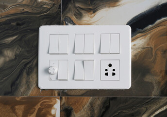 Indian light and fan switches on a faux marble wall.