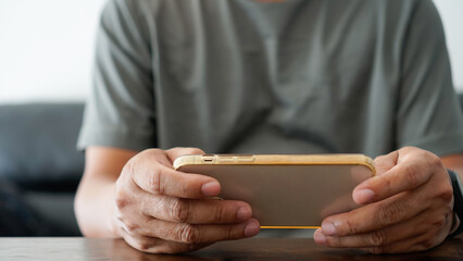 A man typing on a touchscreen cell phone in a living room, casual businessman carrying and utilizing smartphone for SMS messaging. Concept for a business, way of life, technology, and social media net