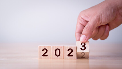 2023 Strategy, Business, Plan, Growth, Investment, Target, Goal, Success, Development, Background Concept. Businessman hand flipping wooden cube block change year 2022 to 2023 with goal, target symbol