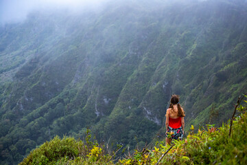 Obraz premium girl in pigtails stands at the top of the kuliouou ridge trail admiring the panorama of oahu, honolulu and the hawaiian mountains; hiking in the mountains in hawaii, holiday in hawaii