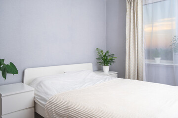 Beautiful modern white room furnished with green plants with sunset or sunrise outside the window. Beautiful home interior. Beautiful hotel room with a view of beautiful sunsets and sunrises.