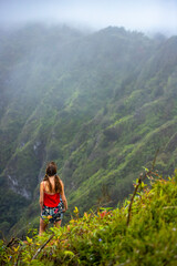 girl in pigtails stands at the top of the kuliouou ridge trail admiring the panorama of oahu, honolulu and the hawaiian mountains; hiking in the mountains in hawaii, holiday in hawaii