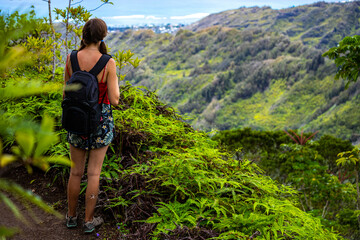 Naklejka premium hiker girl with backpack admires hawaii panorama from kuliouou ridge trail, hiking through mountains on oahu near honolulu