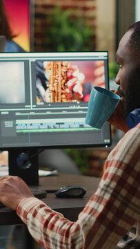 Vertical Video: African American Employee Editing Video Content On Multimedia Software, Using Focus Lighting And Color Grading. Male Filmmaker Working On Movie Montage Edit On Pc Multi Monitors.