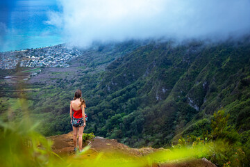 girl in pigtails stands at the top of the kuliouou ridge trail admiring the panorama of oahu, honolulu and the hawaiian mountains; hiking in the mountains in hawaii, holiday in hawaii