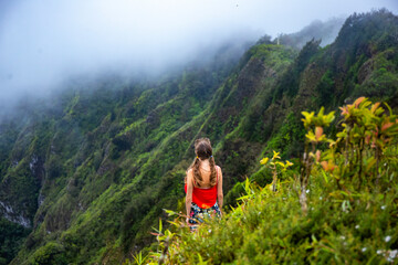 Naklejka premium girl in pigtails stands at the top of the kuliouou ridge trail admiring the panorama of oahu, honolulu and the hawaiian mountains; hiking in the mountains in hawaii, holiday in hawaii