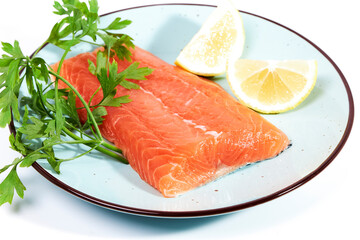 Salmon, fresh raw fish fillets together with parsley and lemon on a plate