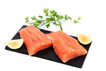 Salmon, fresh raw fish fillets with parsley and lemon on a slate