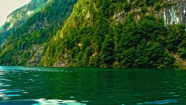 Bootstour am Königsee in Bayern mit sanftem Kameraschwenk zum bewaldeten, bergigen, grünen und naturbelassenen Seeufer