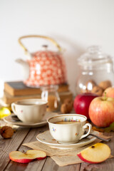 Tavolo imbandito per l'ora del tè o colazione con tazze, teiera e mele