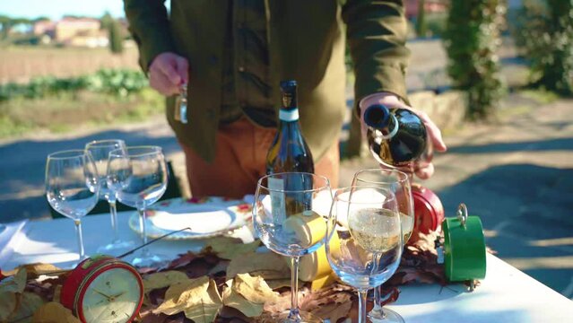 Italian sommelier pouring aged white wine in crystal goblet in Tuscany countryside under the open air, exclusive Italian wine bottles for special guests and tourists, autumn banquet table at the