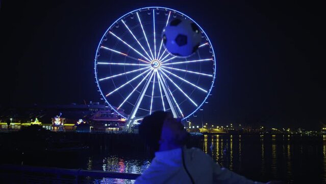 Football Freestyle with Man Heading Soccer Ball by Ferris Wheel