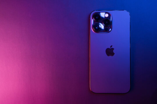 Closeup of iPhone 14 Pro Max Space Black isolated on black background illuminated by blue and pink lights. Low light. 3 featured cameras. Selective focus