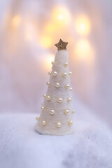 white christmas tree decoration with pearls infront of golden bokeh